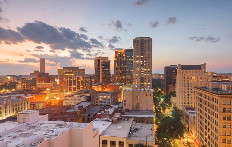An outdoor photo of Birmingham, Alabama with buildings in the background and clouds in the sky.