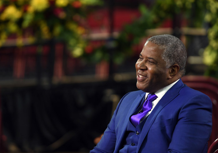 Robert F. Smith smiles while wearing a blue suit during an interview.